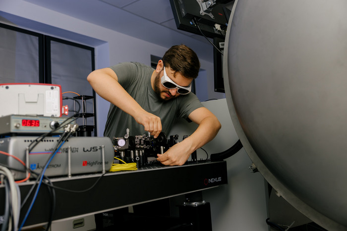 Ein Wissenschaftler im Labor justiert optische Komponenten in Vorbereitung von laserspektroskopischen Messungen.