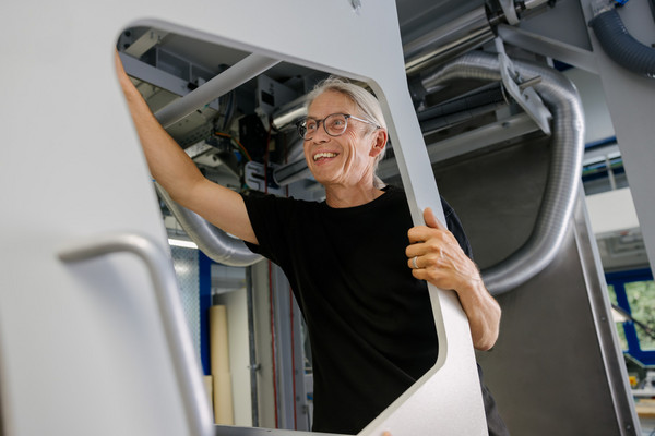 Technischer Mitarbeiter arbeitet an der Rolle-zu-Rolle Anlage zur Fertigung von transparenten flexiblen Verpackungsfolien für Dünnschichtphotovoltaik.