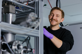 Anschluss einer neuen Gasflasche am Gasverteiler des Einzelionenimplanters. Foto: Erik Kazak Ein Wissenschaftler schließt eine neuen Gasflasche am Gasverteiler des Einzelionenimplanters an.